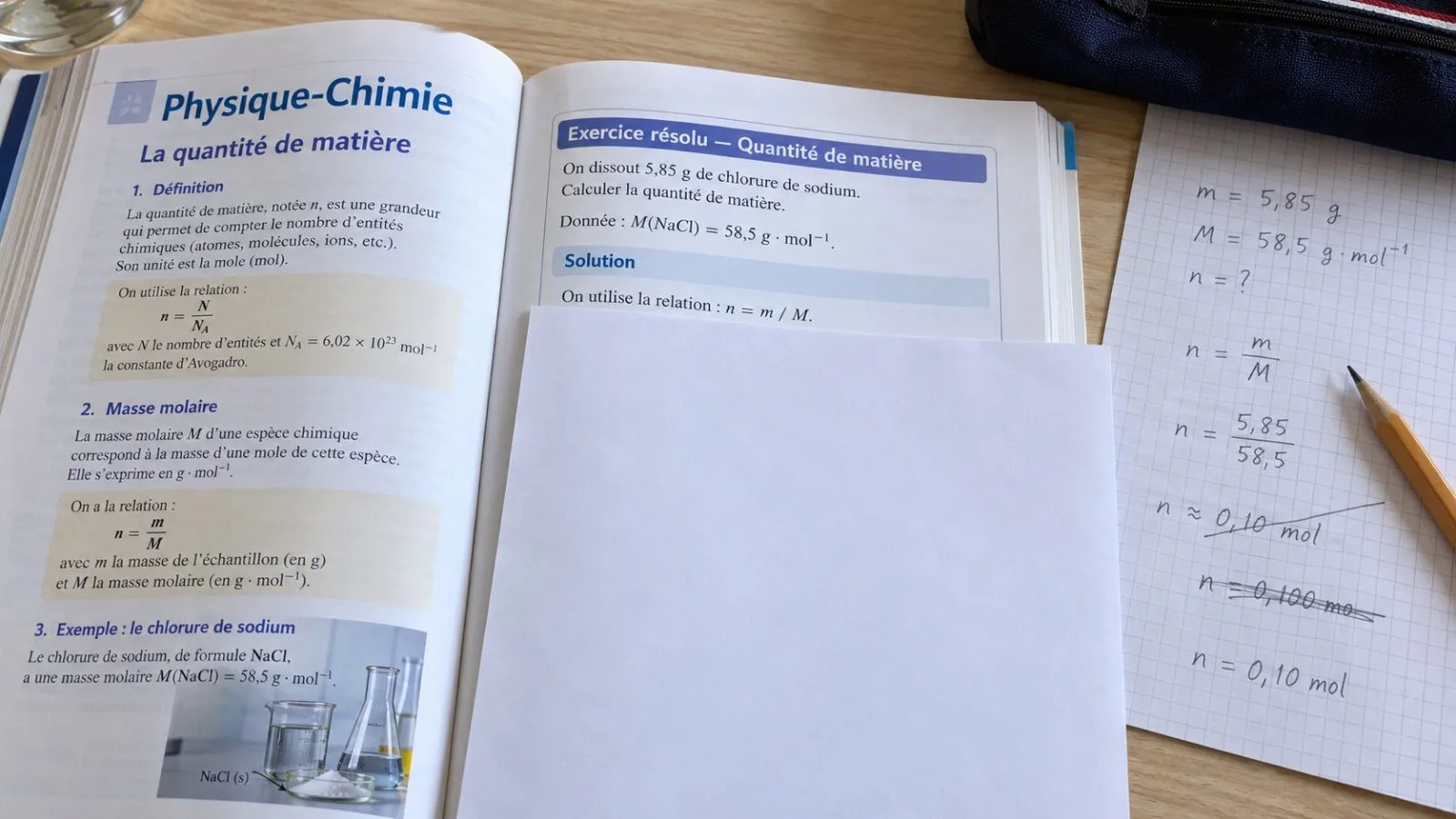 Manuel de physique-chimie ouvert sur un exercice résolu dont la solution est cachée par une feuille, sauf la première ligne